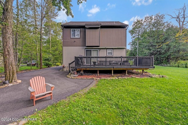 back of house featuring a deck, a yard, and driveway