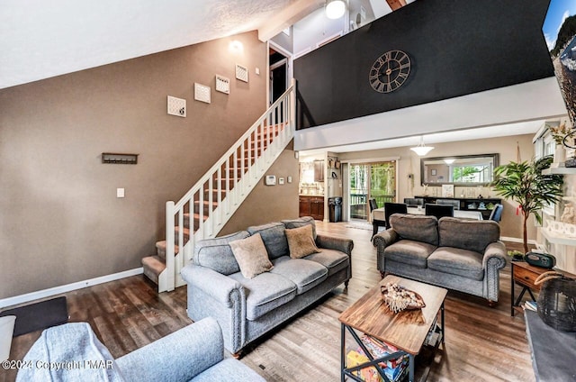 living room with high vaulted ceiling, baseboards, stairway, and wood finished floors