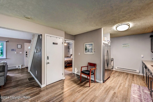 kitchen with baseboard heating, wood finished floors, and freestanding refrigerator