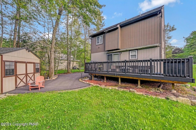 back of property featuring a storage shed, a yard, a deck, and an outdoor structure