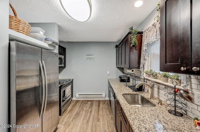 kitchen with appliances with stainless steel finishes, a baseboard radiator, a sink, and dark brown cabinetry