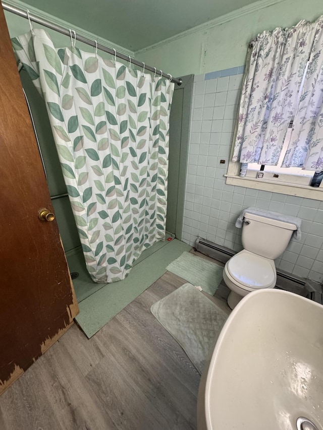 bathroom with tile walls, ornamental molding, a shower stall, and wood finished floors