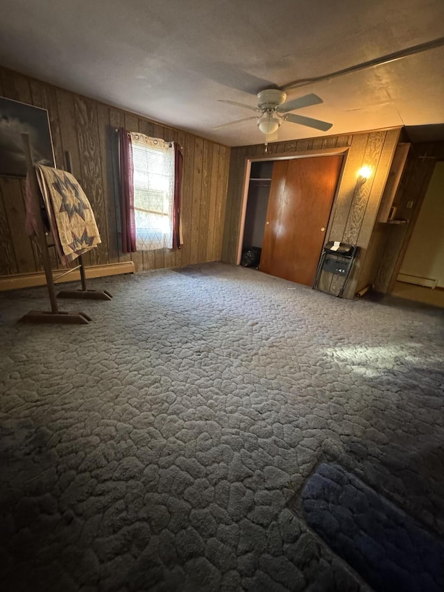 unfurnished bedroom with wooden walls, carpet, and a baseboard radiator