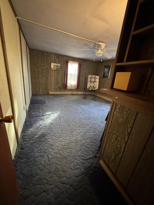 basement featuring baseboards, a ceiling fan, carpet flooring, and wood walls