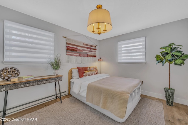 bedroom featuring baseboards, a baseboard heating unit, and wood finished floors