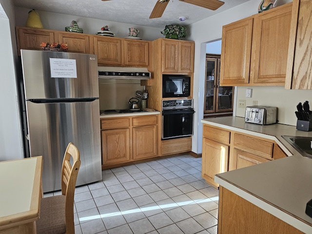 kitchen with a textured ceiling, extractor fan, light tile patterned flooring, a toaster, and black appliances