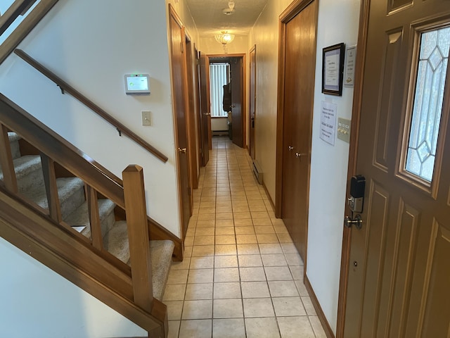 hall with light tile patterned floors, stairway, and baseboards