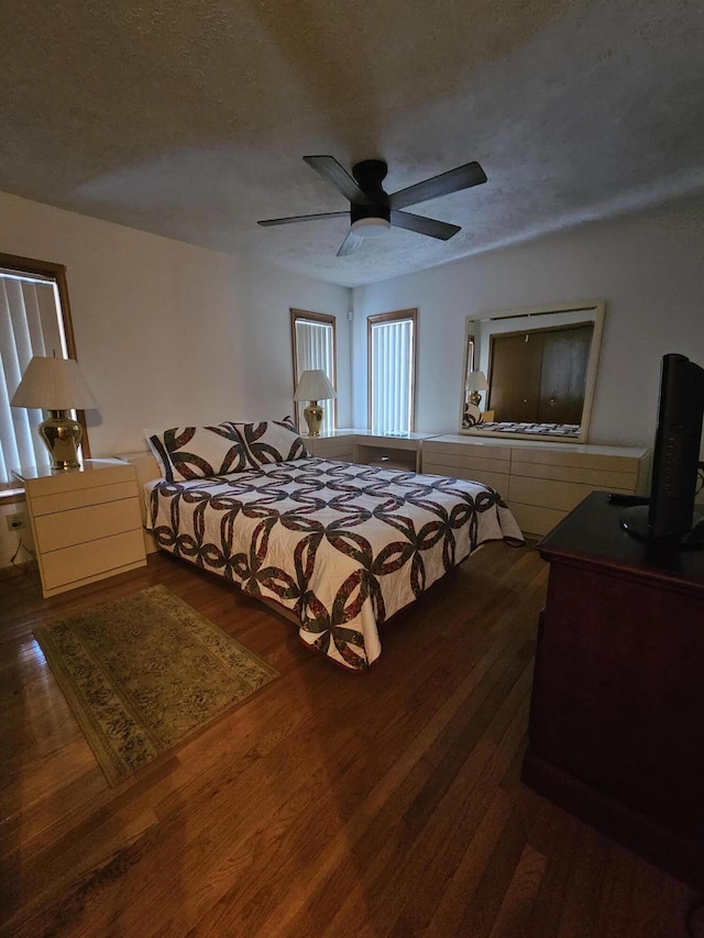 bedroom featuring ceiling fan, a textured ceiling, and dark wood-style flooring