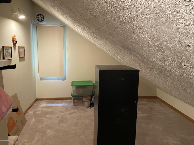 bonus room featuring a textured ceiling, carpet floors, visible vents, baseboards, and vaulted ceiling