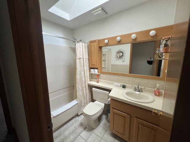 full bath featuring a skylight, toilet, tile patterned floors, vanity, and backsplash