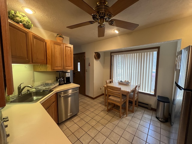 kitchen featuring a textured ceiling, a baseboard heating unit, stainless steel appliances, a sink, and light countertops