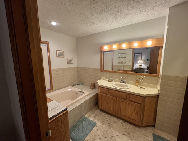 bathroom featuring a textured ceiling, a garden tub, tile walls, vanity, and tile patterned floors