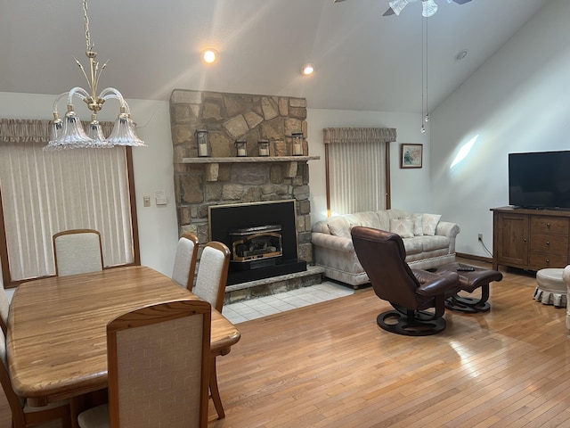 living room featuring lofted ceiling, hardwood / wood-style flooring, a fireplace, and ceiling fan with notable chandelier