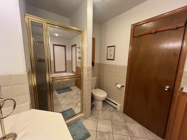 full bath featuring toilet, a shower with door, a baseboard radiator, a textured ceiling, and tile walls