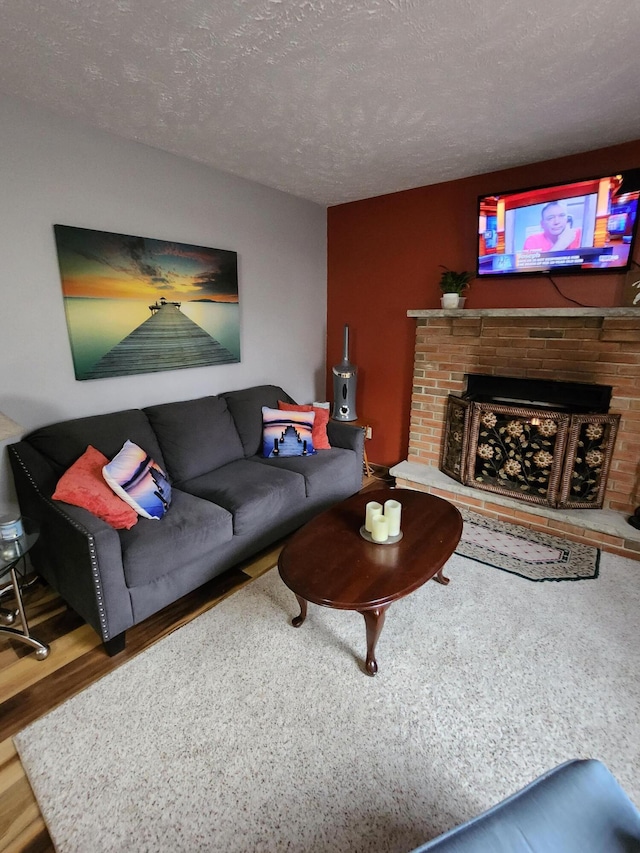 living area featuring a brick fireplace, wood finished floors, and a textured ceiling