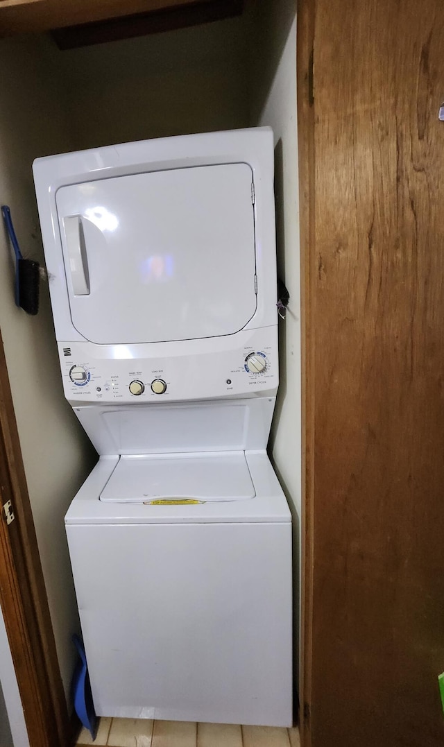 laundry room featuring light tile patterned flooring, stacked washer / dryer, and laundry area