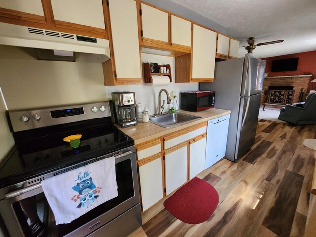457 Maxatawny Dr, Pocono Lake, PA 18347 - kitchen with appliances with stainless steel finishes, under cabinet range hood, a fireplace with raised hearth, light wood finished floors, and ceiling fan