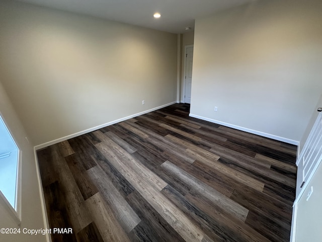 empty room with dark wood-style flooring, baseboards, and recessed lighting