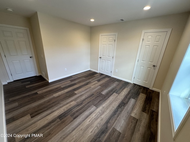 empty room featuring recessed lighting, dark wood-style floors, baseboards, and visible vents
