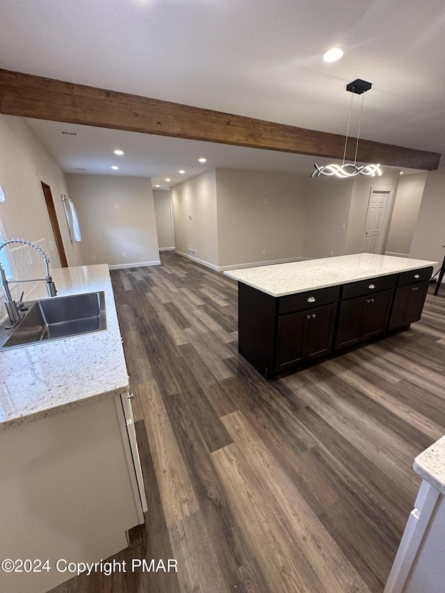 kitchen featuring dark wood-style flooring, a sink, a kitchen island, and beam ceiling