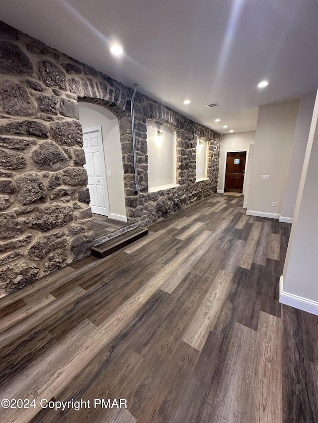unfurnished living room featuring visible vents, baseboards, wood finished floors, recessed lighting, and arched walkways
