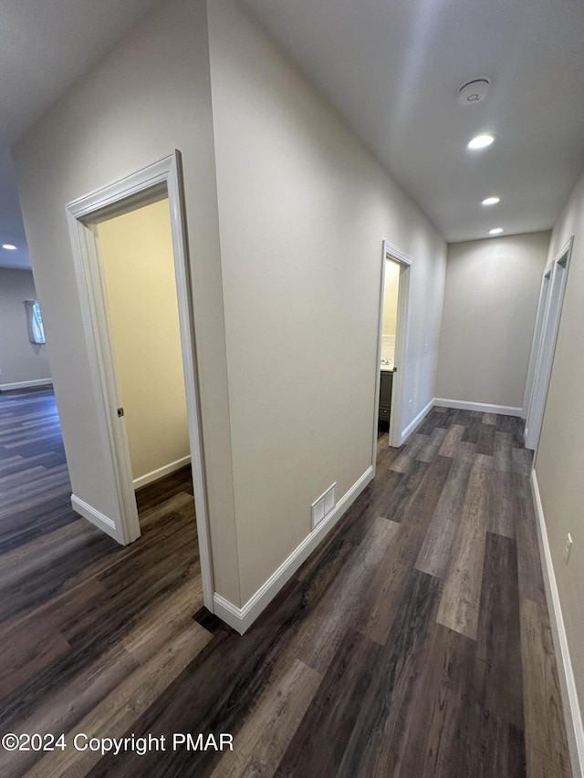 corridor featuring recessed lighting, dark wood-type flooring, baseboards, and visible vents