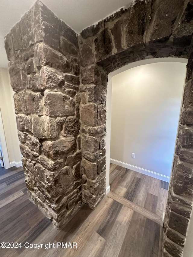 details featuring arched walkways, baseboards, and wood finished floors