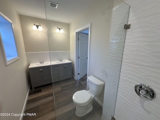bathroom with toilet, a sink, wood finished floors, visible vents, and double vanity