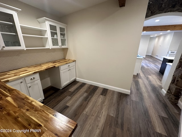 unfurnished office with dark wood-type flooring, arched walkways, baseboards, and recessed lighting