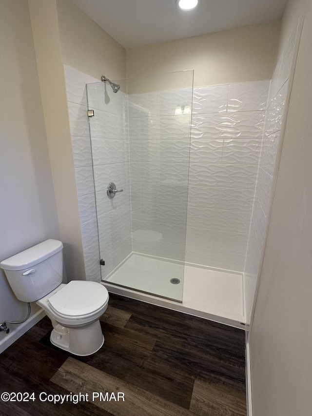 bathroom with wood finished floors, toilet, and walk in shower