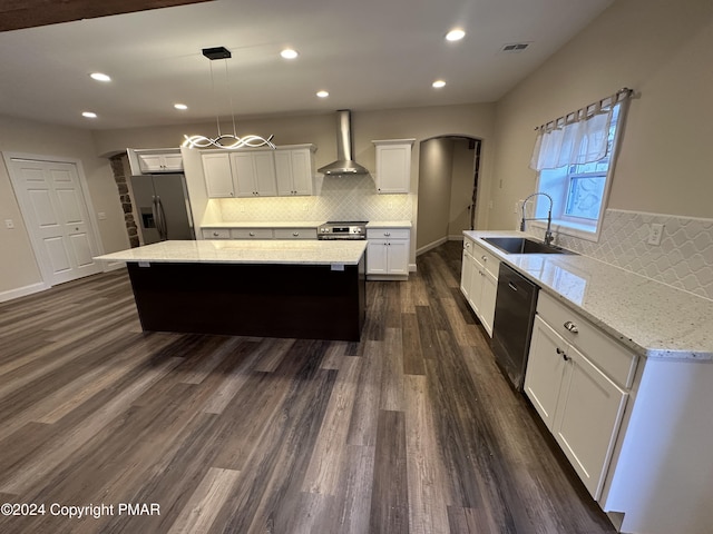 kitchen with a sink, wall chimney exhaust hood, a center island, stainless steel appliances, and visible vents