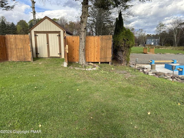 view of yard featuring an outdoor structure, a storage unit, and fence