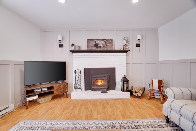 living room with a baseboard heating unit, recessed lighting, wood finished floors, and a decorative wall