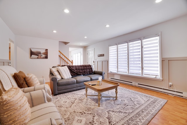 living room featuring a wainscoted wall, a baseboard radiator, recessed lighting, wood finished floors, and stairs