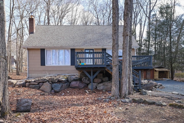 chalet / cabin featuring stairs, a shingled roof, a chimney, and a wooden deck