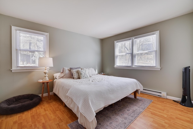 bedroom with light wood finished floors, multiple windows, a baseboard radiator, and baseboards