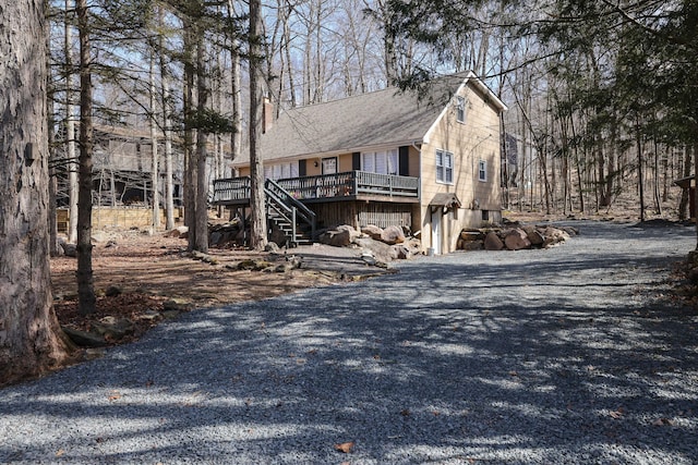 exterior space featuring stairway, a chimney, gravel driveway, and a wooden deck