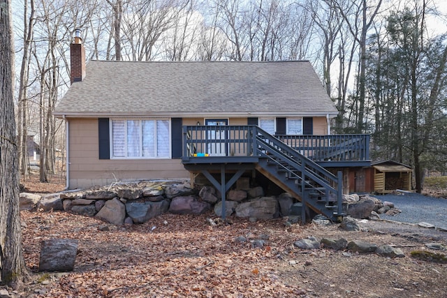 chalet / cabin featuring stairs, roof with shingles, a chimney, and a wooden deck