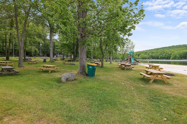 surrounding community with playground community, a yard, and a water view