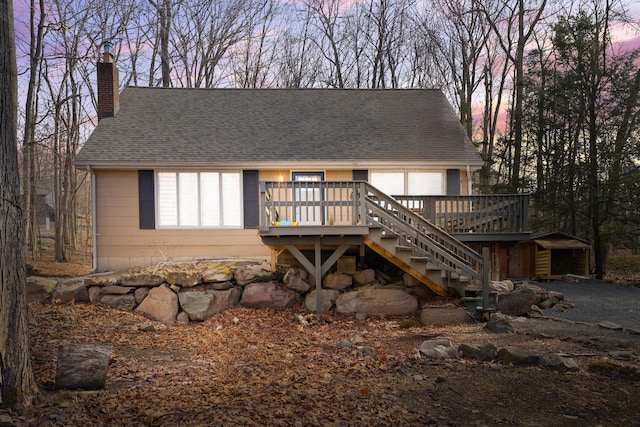 rear view of house with a shingled roof, stairs, a chimney, and a wooden deck