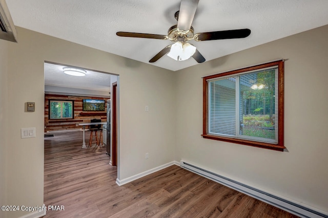 unfurnished room featuring a textured ceiling, wood finished floors, ceiling fan, and a baseboard radiator