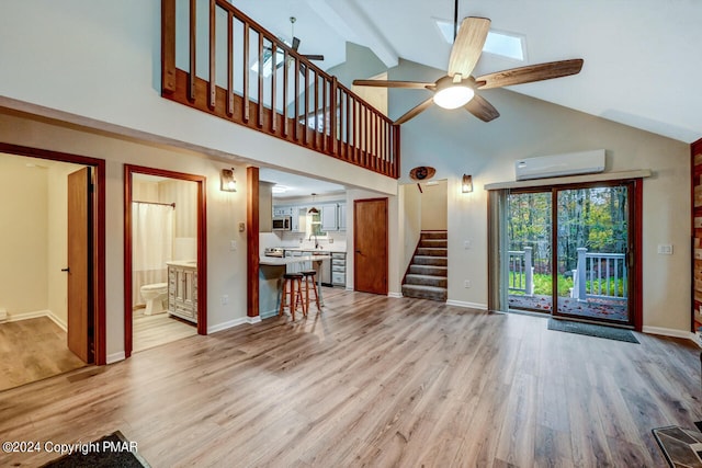 unfurnished living room featuring an AC wall unit, light wood-style flooring, a ceiling fan, stairway, and baseboards