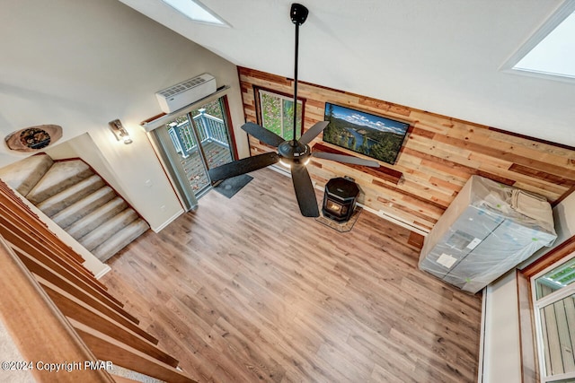 interior space with stairway, wood walls, a skylight, wood finished floors, and high vaulted ceiling