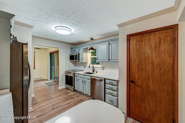 kitchen featuring a sink, backsplash, a textured ceiling, stainless steel appliances, and light wood finished floors