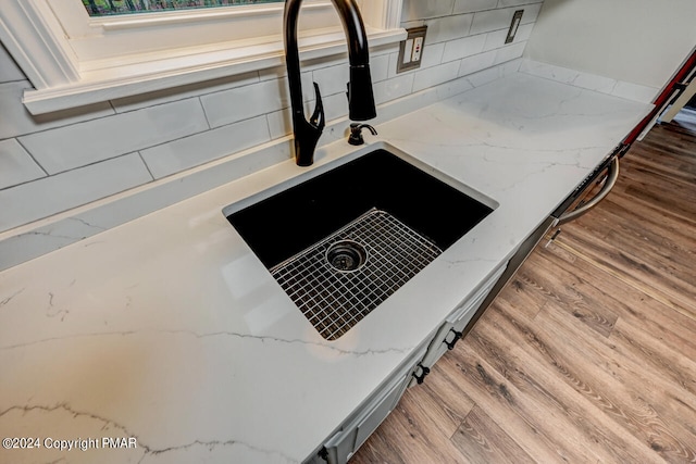 interior details featuring light stone counters, a sink, and wood finished floors