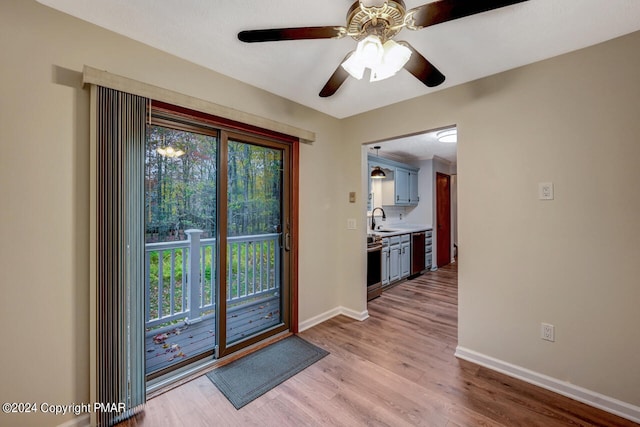 doorway to outside with a ceiling fan, light wood-type flooring, baseboards, and a sink