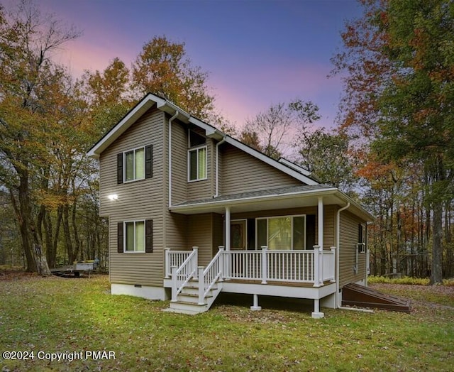 view of front of house featuring a porch, a lawn, and crawl space