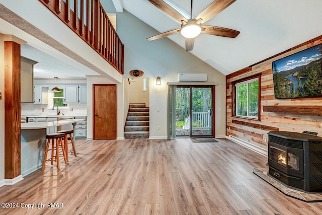 living room featuring stairway, a wood stove, an AC wall unit, and light wood-style flooring