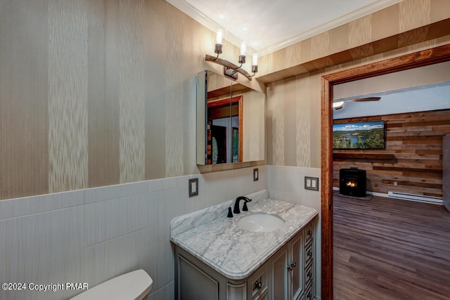 half bath featuring toilet, wood finished floors, wooden walls, crown molding, and vanity