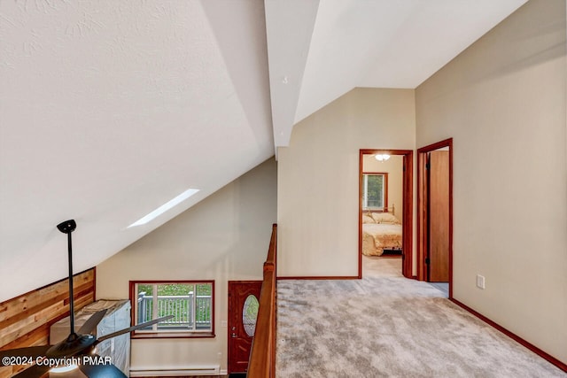 bonus room with a ceiling fan, baseboards, a baseboard radiator, vaulted ceiling with skylight, and carpet flooring